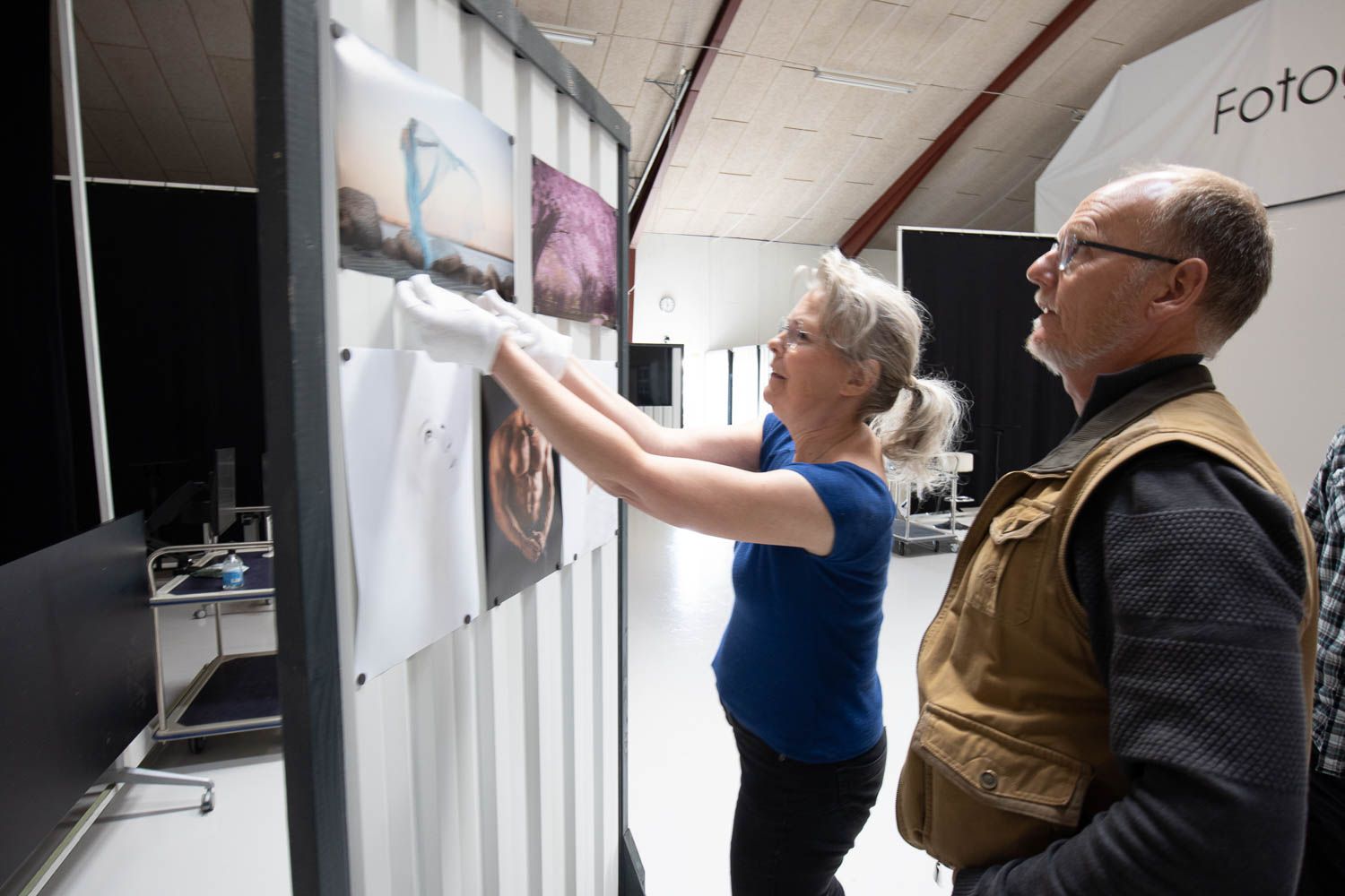 Team members discussing photographs displayed on a gallery wall.