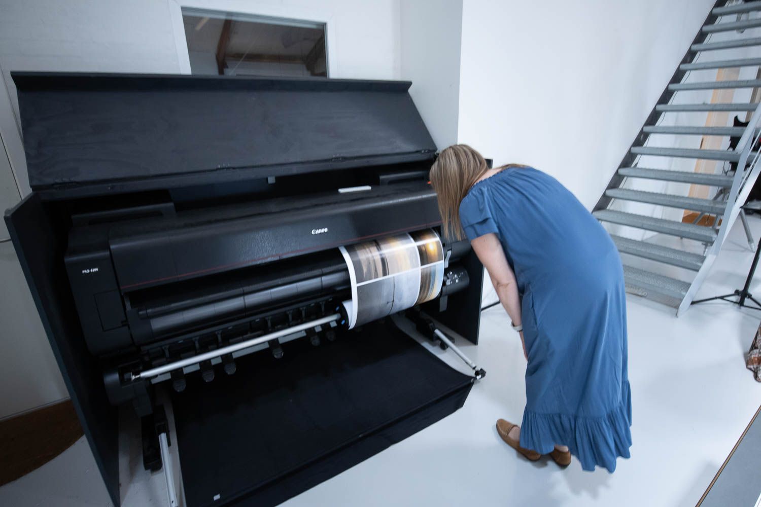 Person examining a large format printer in a professional photography studio.