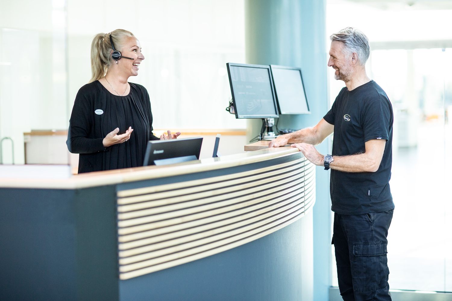 Office workers having a discussion at a modern reception desk in a bright interior.