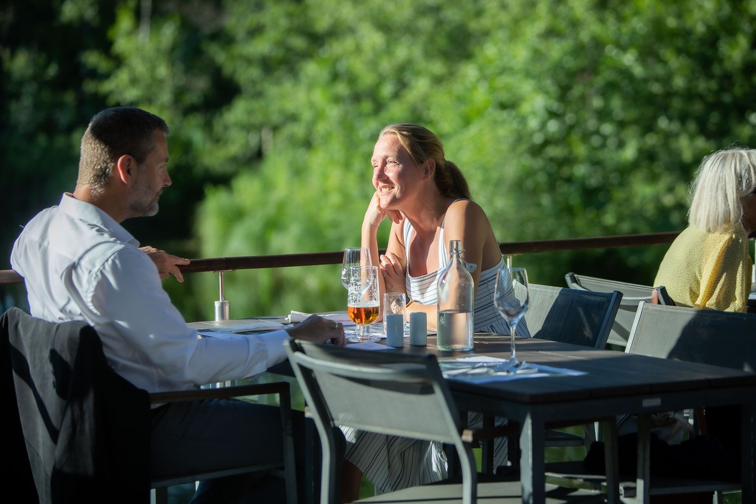 Diners enjoying meals at outdoor tables with waterfront views.