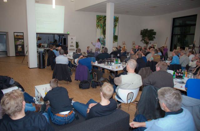 Conference room filled with attendees viewing a presentation in a modern space.