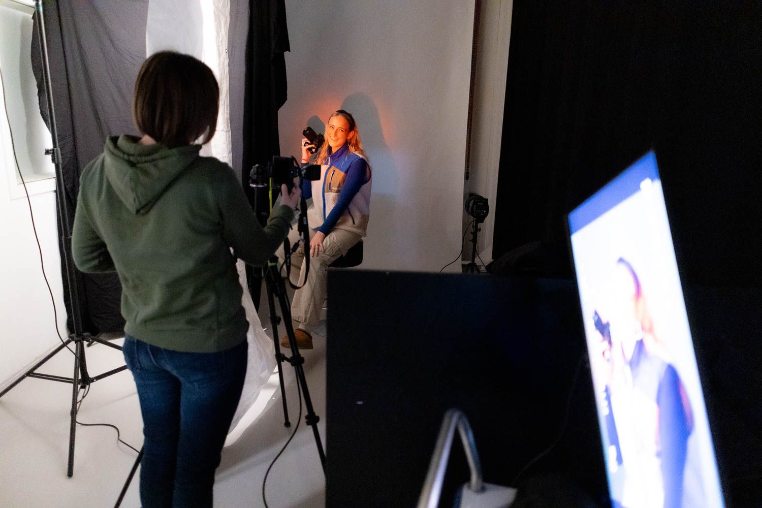 Professional photo studio setup with lighting equipment and backdrop during a photography session.