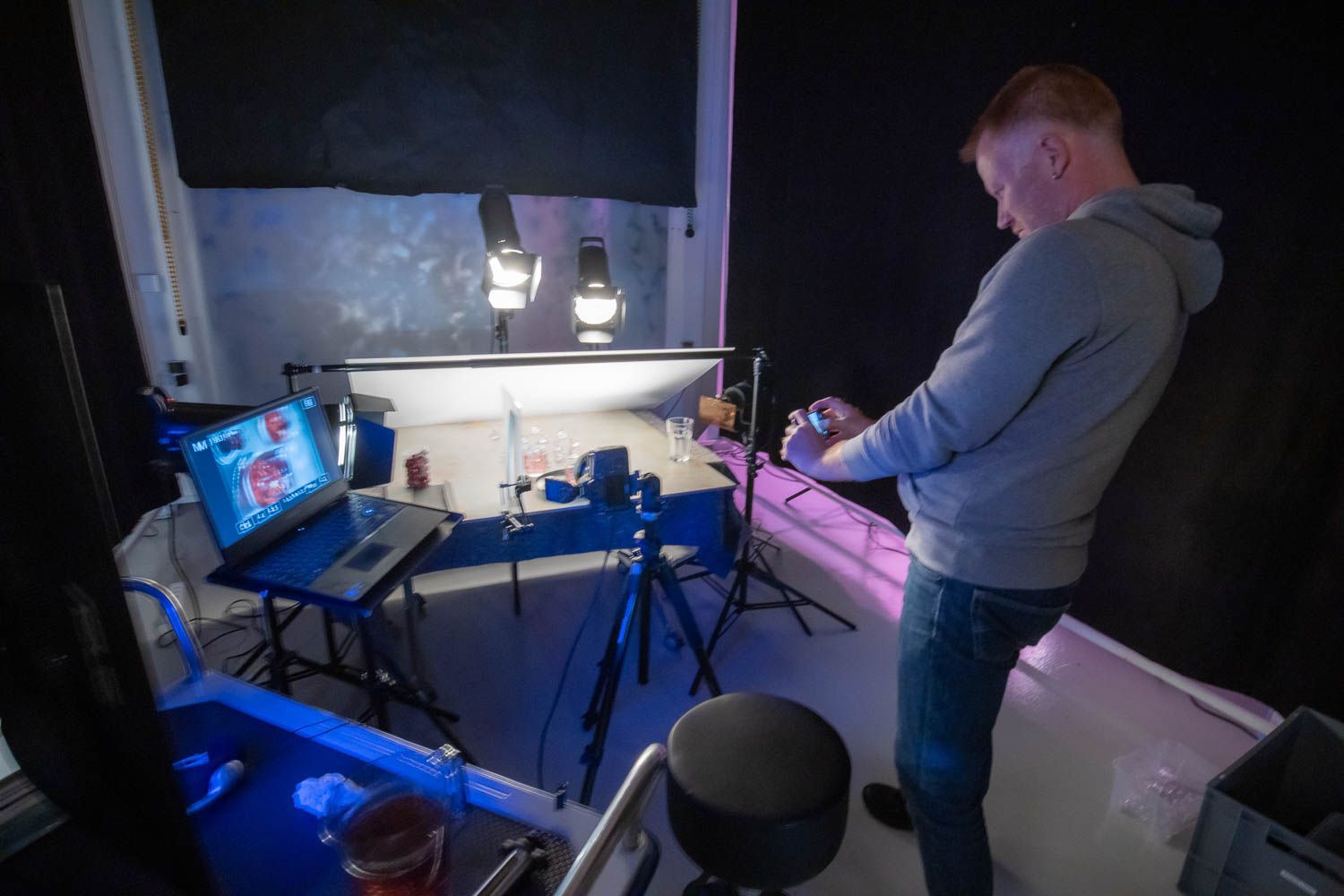 Photography studio with blue lighting effects and professional equipment setup.
