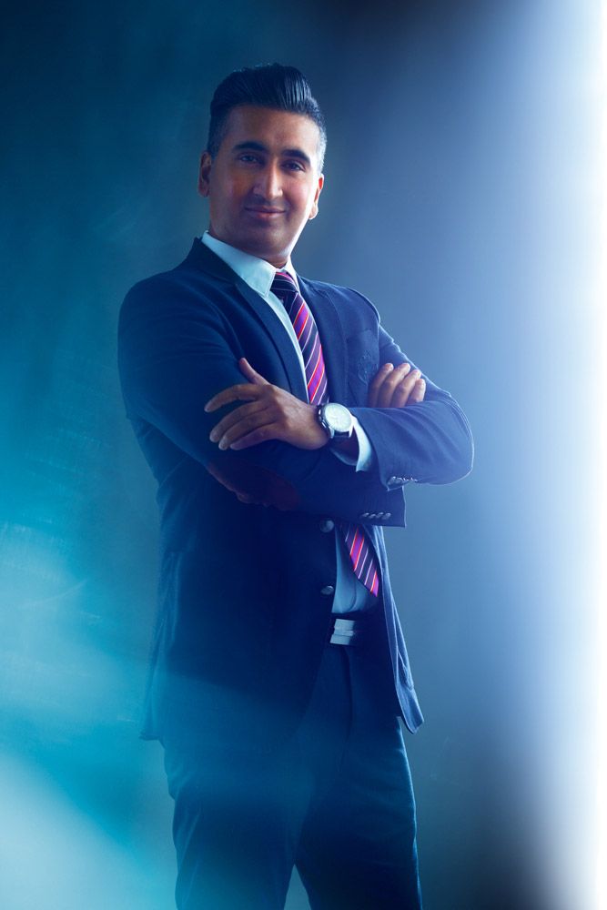 Dynamic business portrait with dramatic side lighting against blue-tinted studio background.