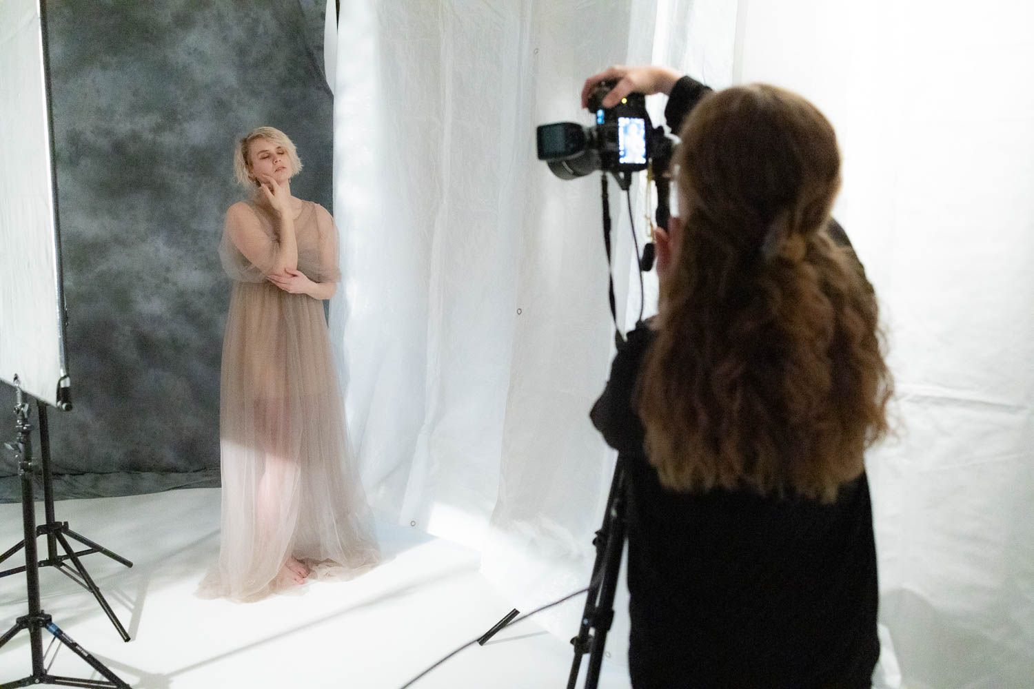 Fashion photography session in progress with white backdrop and studio equipment visible.