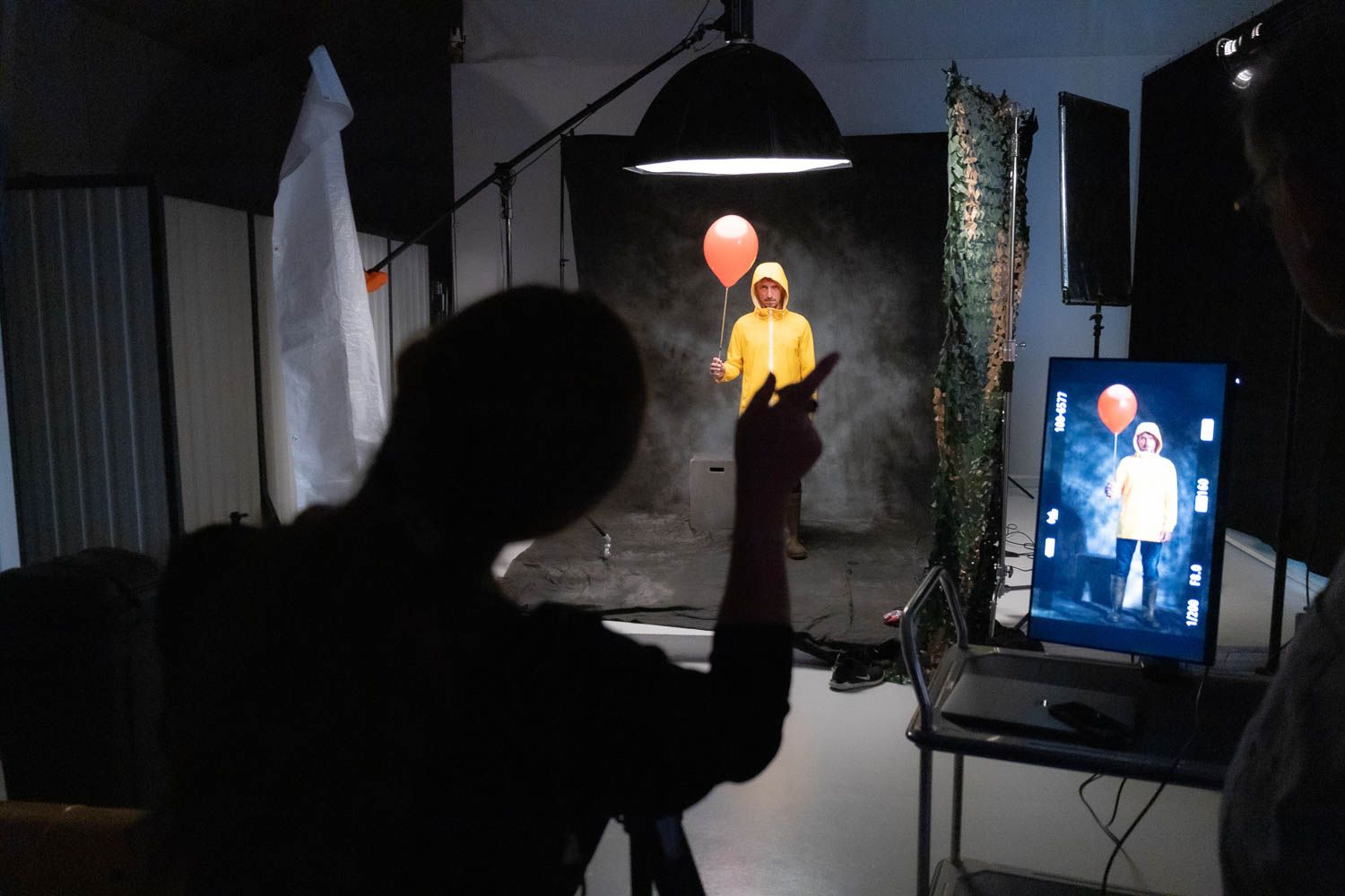 Dark studio space with professional lighting equipment and monitors visible in the background.