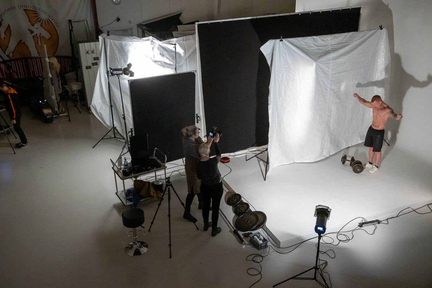 Wide angle view of photography studio showing lighting setup and white backdrop during shoot.