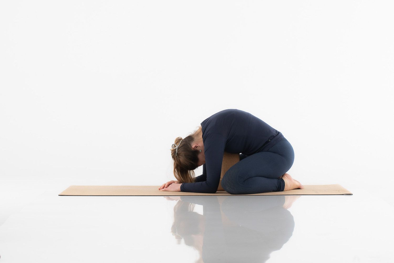 Yoga practitioner performing relaxation poses on wooden platform in navy attire.
