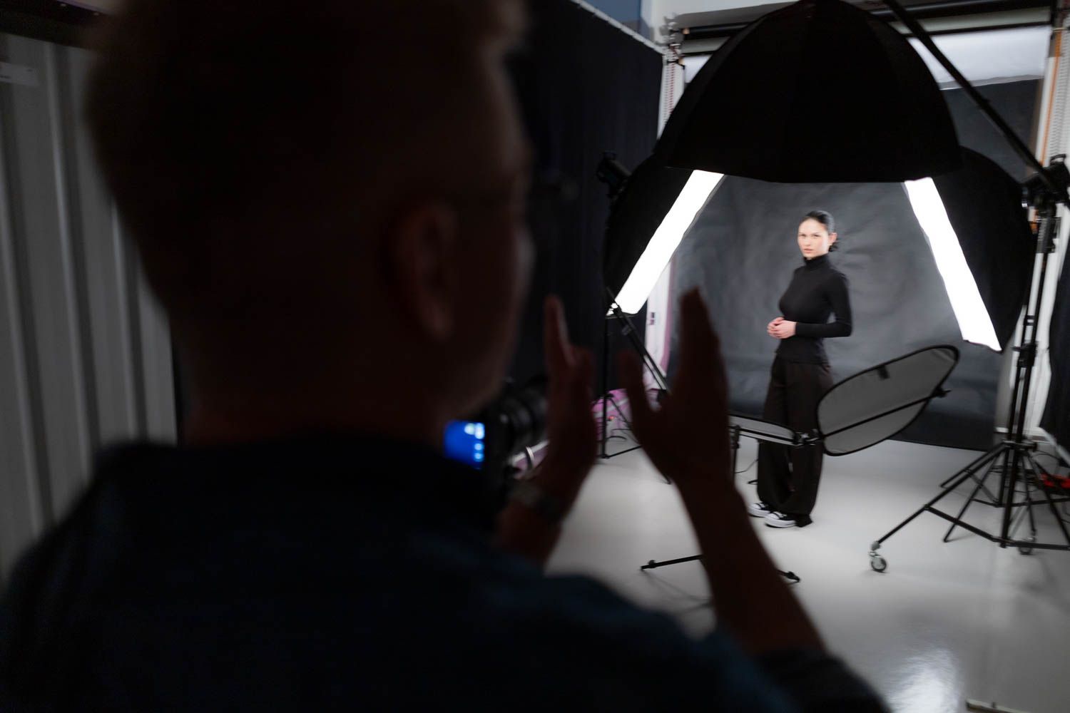 Studio photography session showing camera operators and lighting equipment in silhouette.