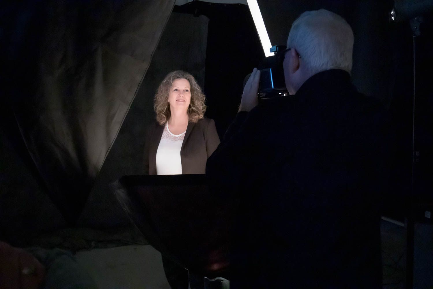 Studio photography session in progress with dramatic lighting and equipment visible.