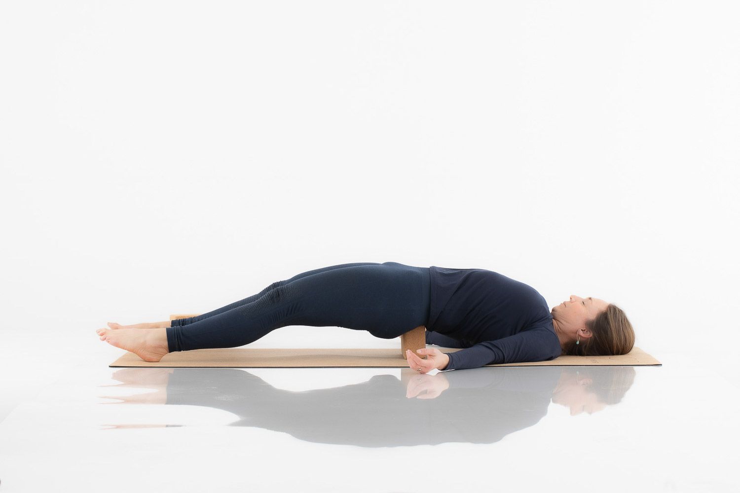 Yoga practitioner lying flat on wooden platform demonstrating restorative pose.