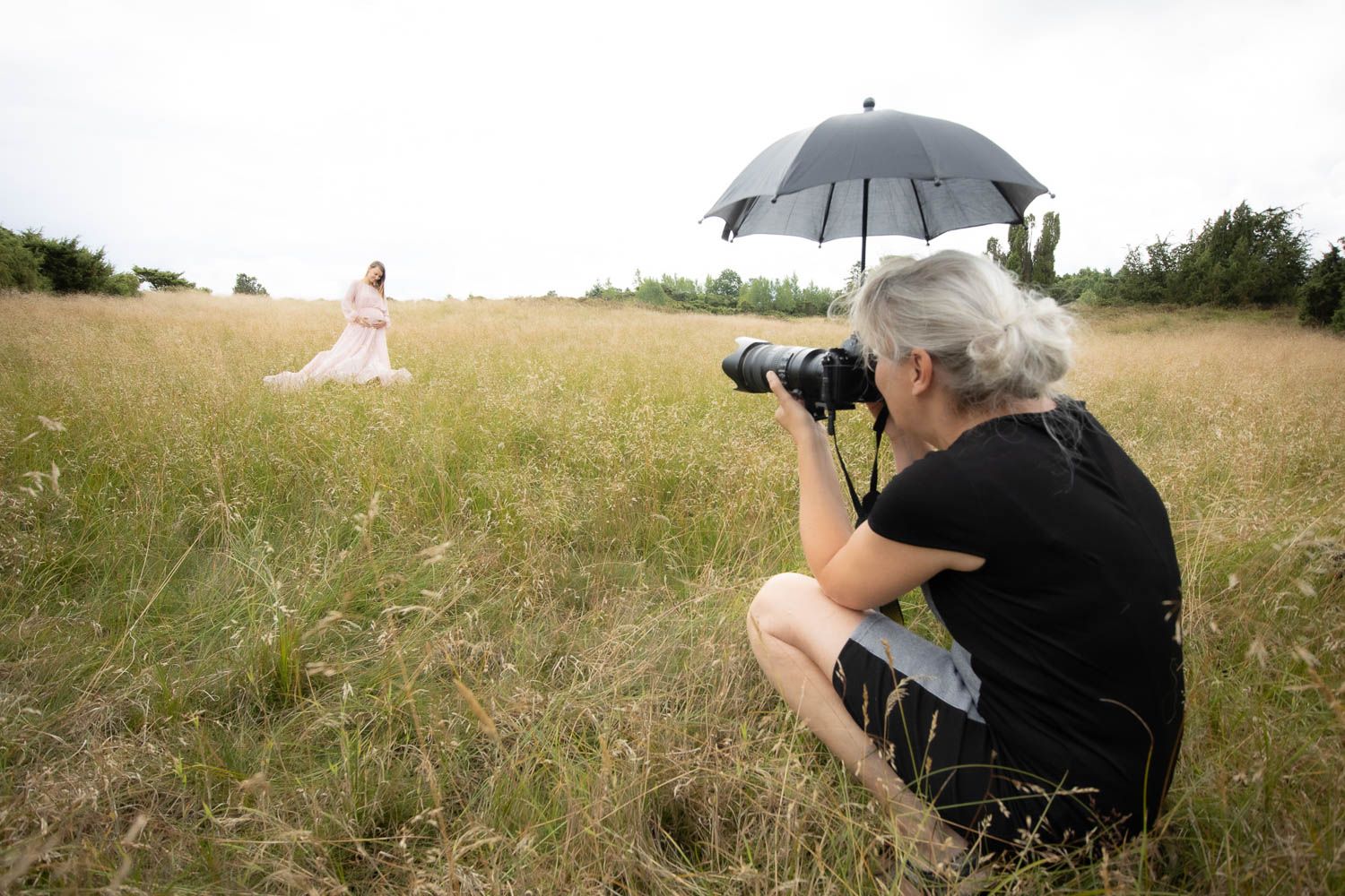 Outdoor photography session in a grassy field with umbrella lighting equipment.