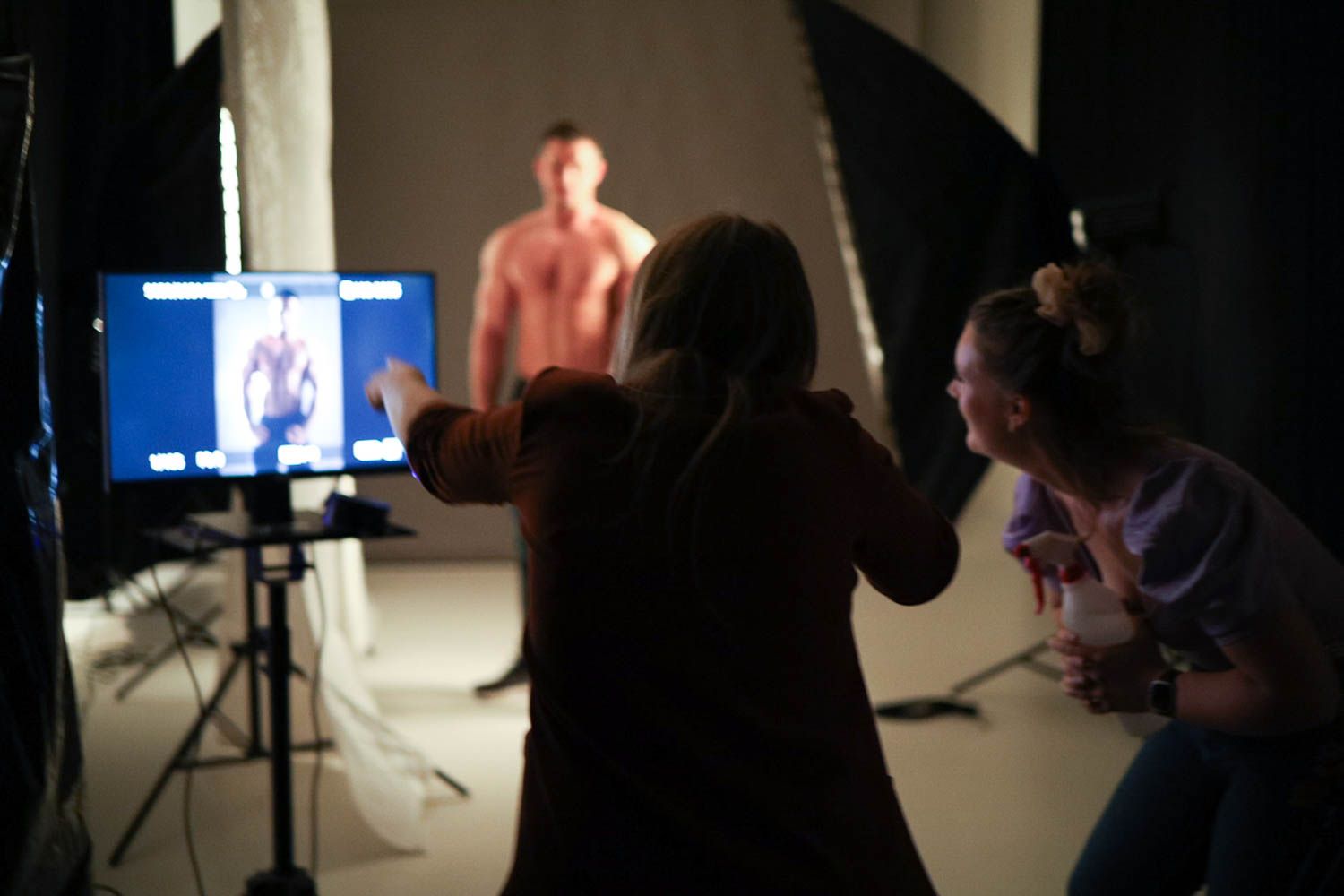 Dark studio space with professional lighting and digital displays during a photo session.