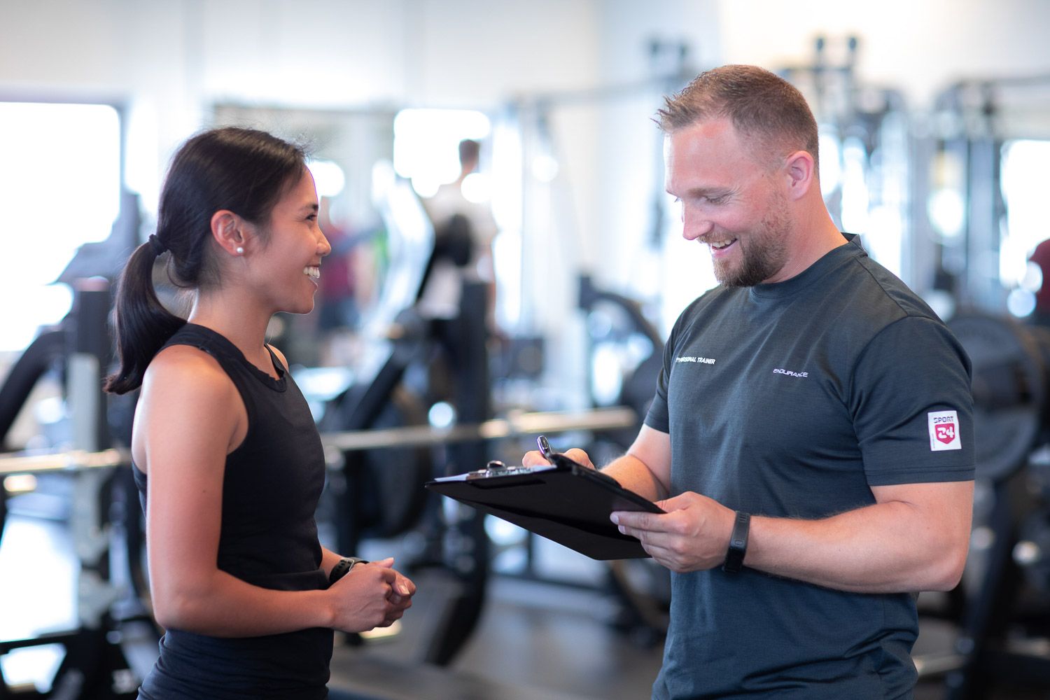 Fitness trainers and clients discussing workout plans in a modern gym setting.