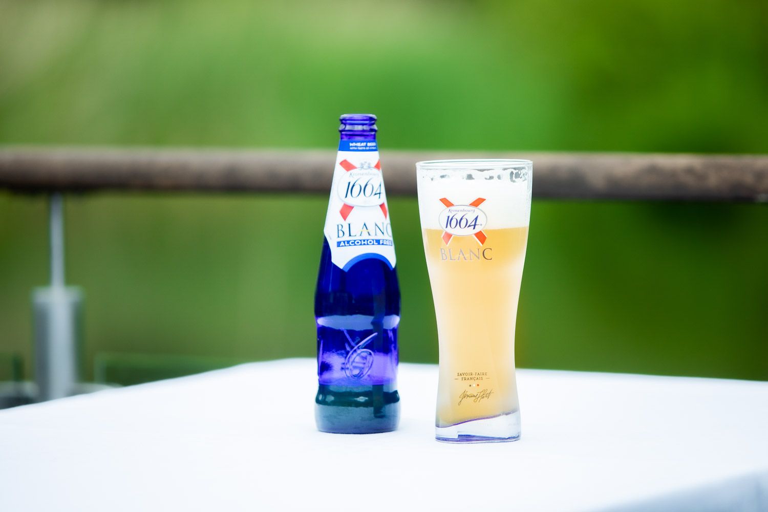 Blue and white beverage bottles arranged on outdoor table against green nature backdrop.