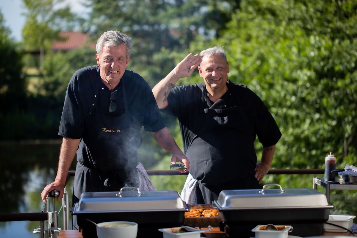 Chefs preparing food at an outdoor grill station during a catered event.