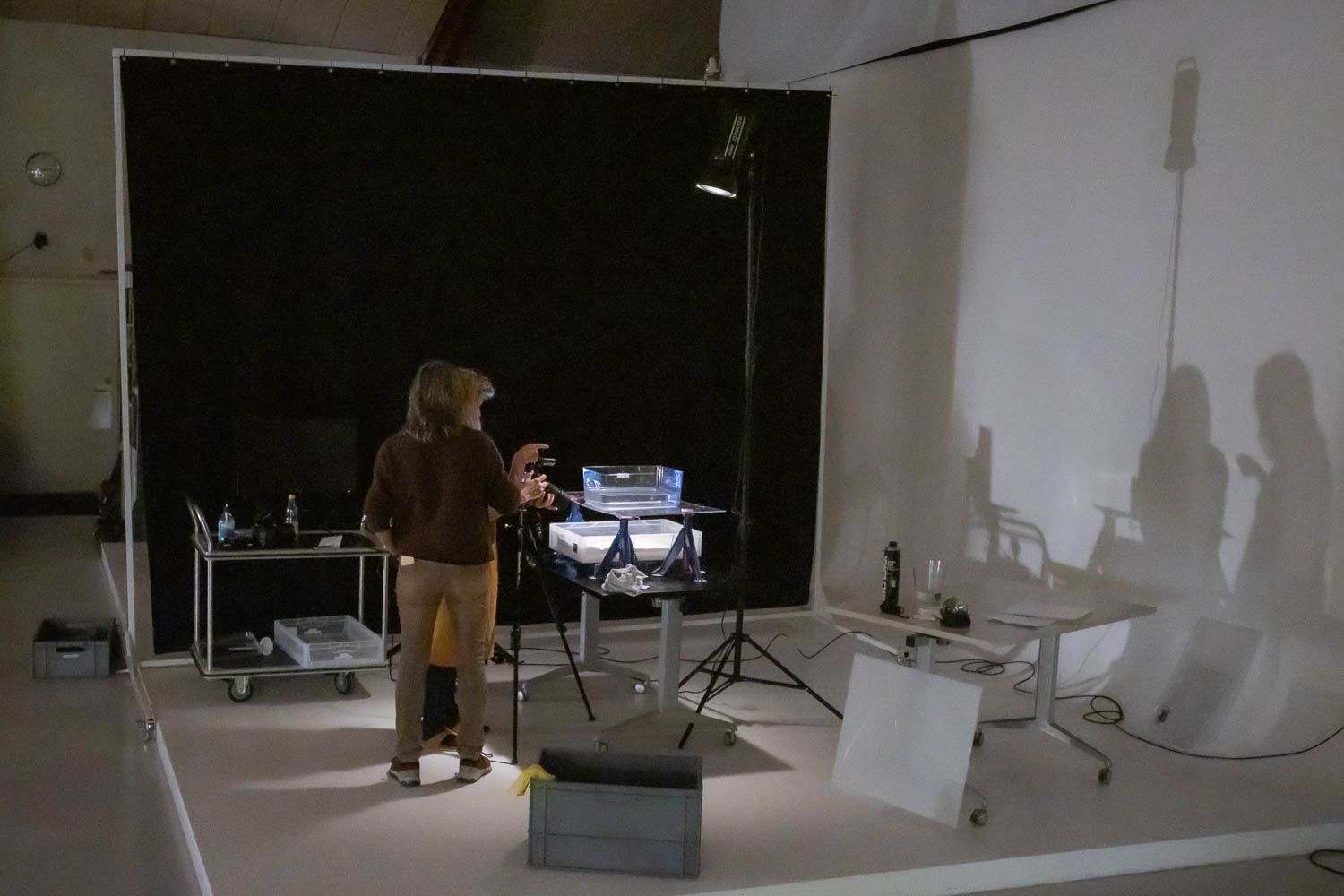 Wide shot of empty photography studio with lighting equipment and white backdrop.