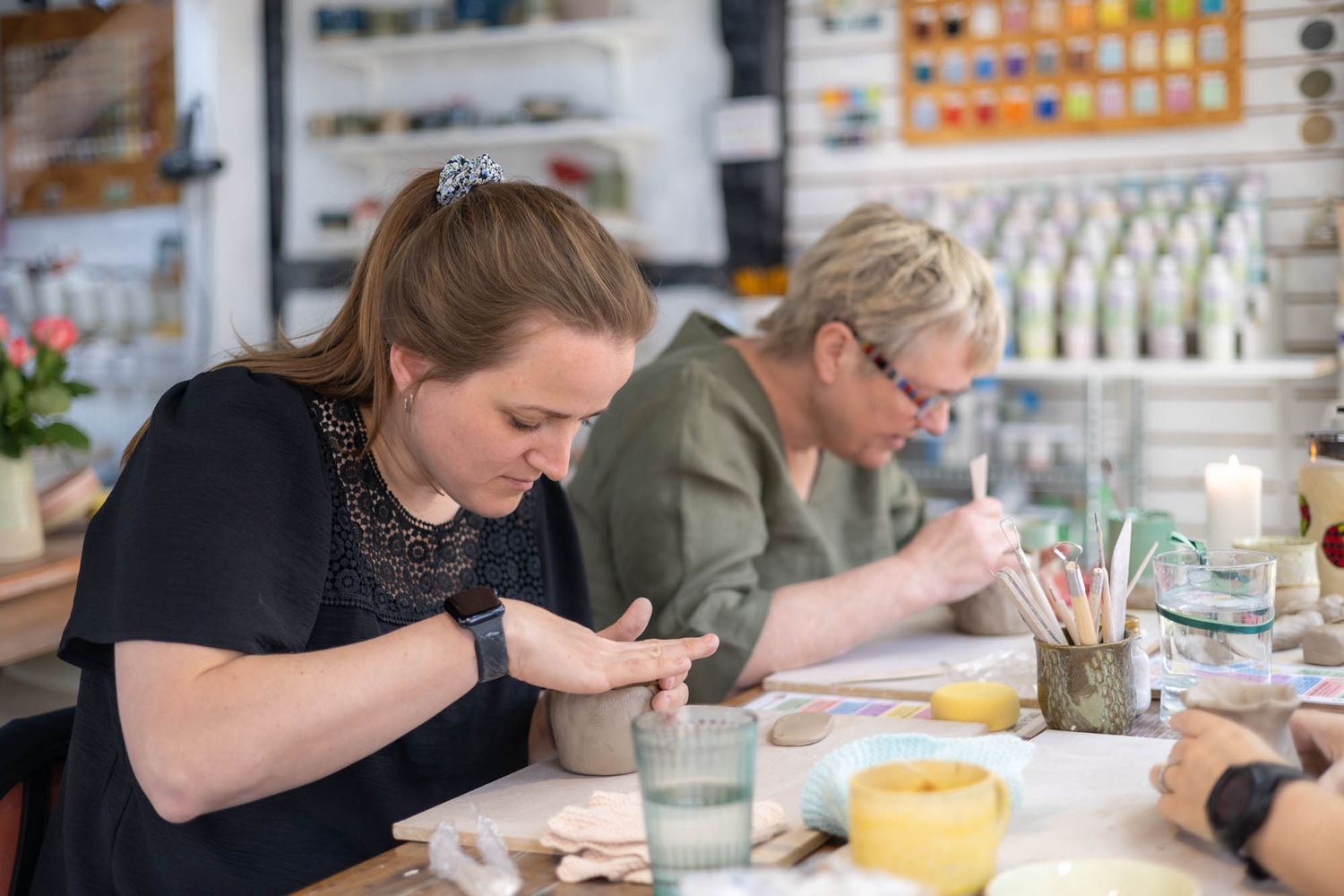 Artists working with clay at a table during a pottery workshop session.