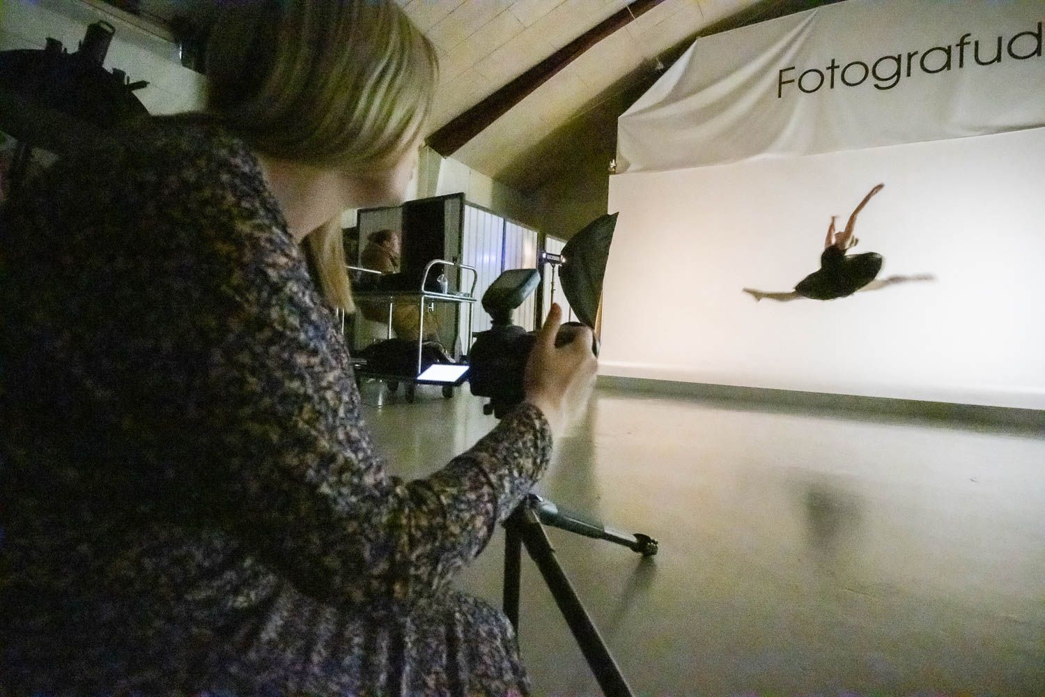 Professional photo studio setup with lighting equipment and white seamless paper backdrop.