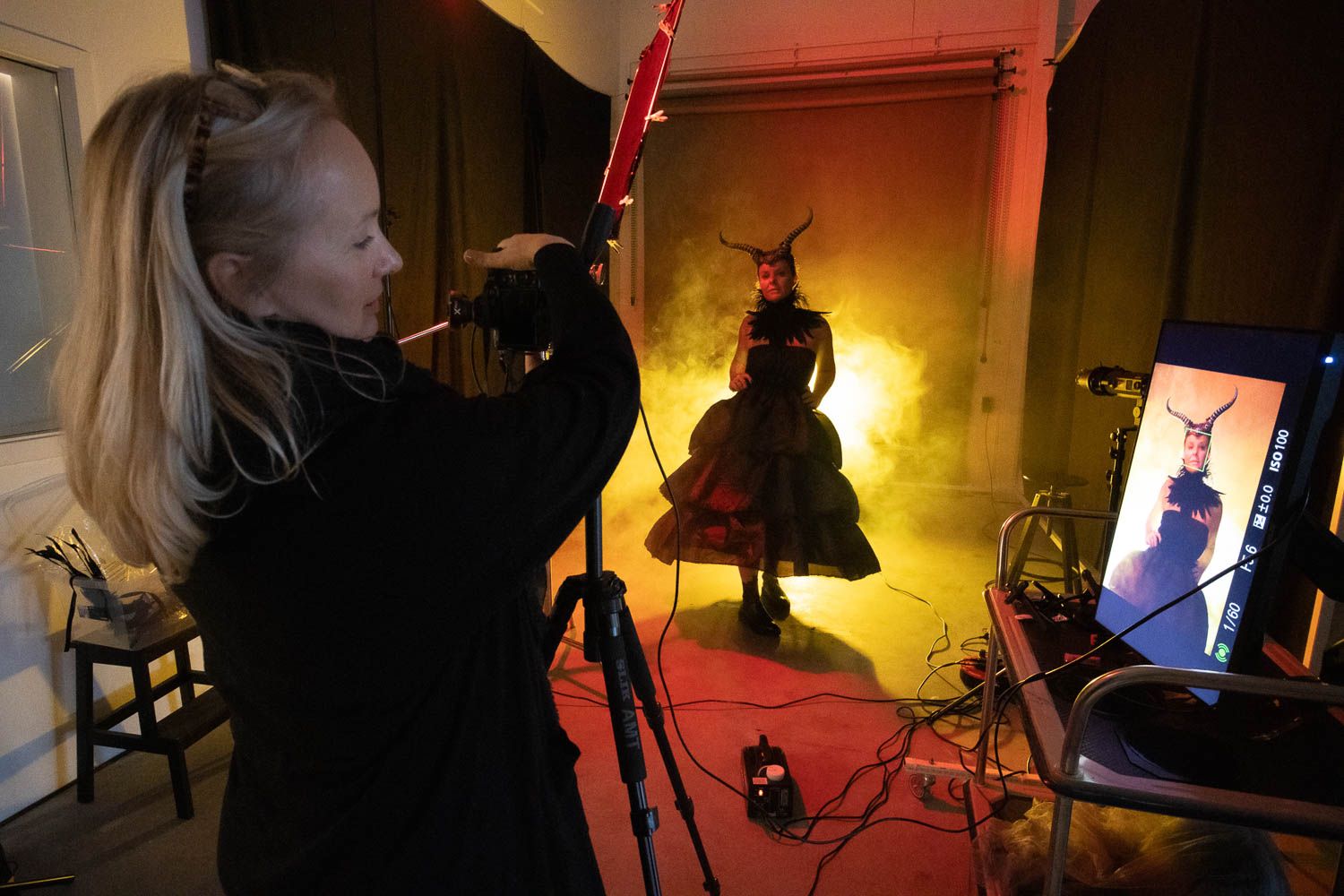 Photography session in progress with dramatic red lighting and silhouetted figure.