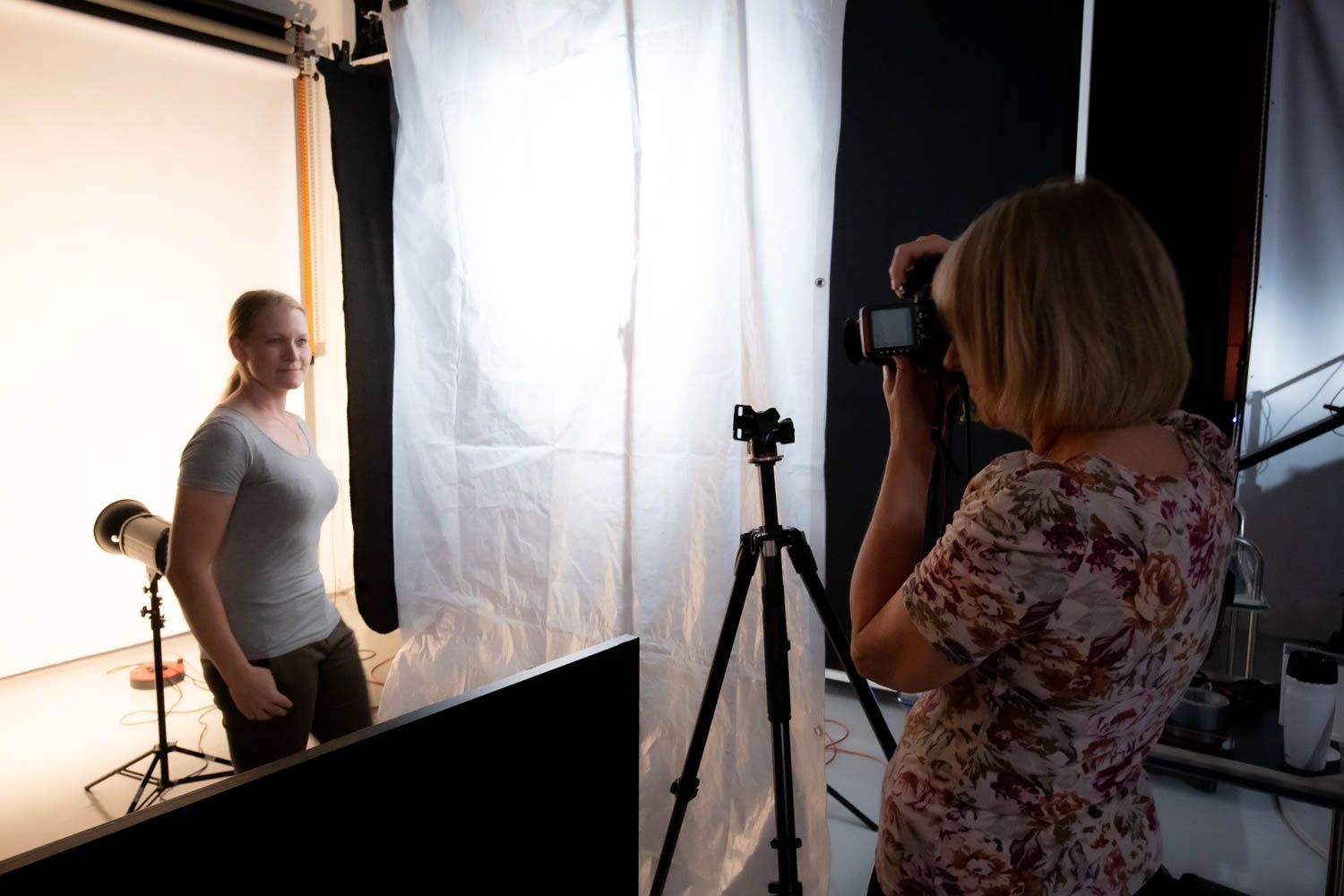 Silhouetted photography equipment and lighting setup against a bright white backdrop in studio.