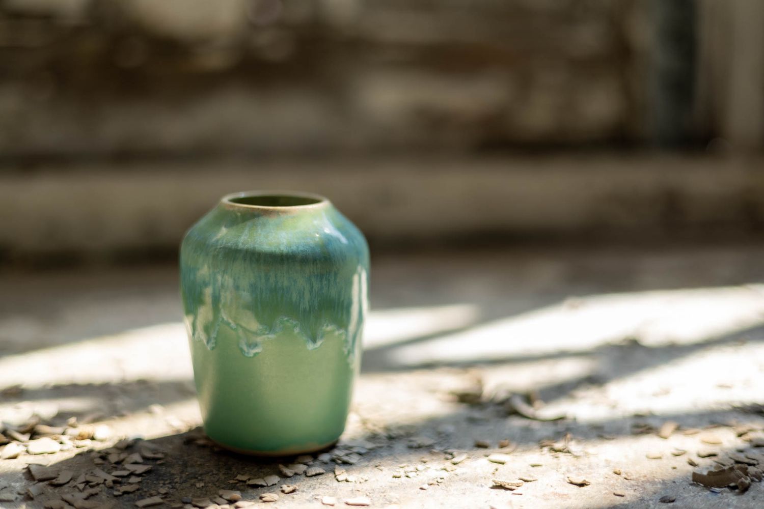 Sunlit pottery studio corner with turquoise ceramic vase catching natural light.