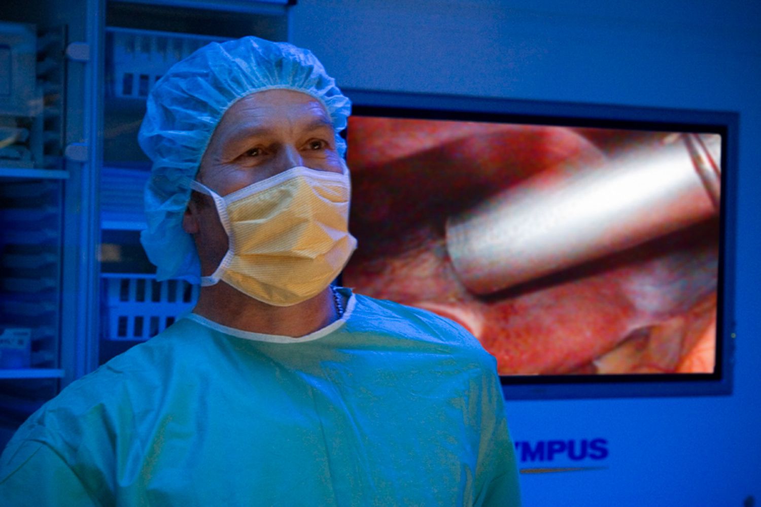 Surgeons working in operating room with medical monitors displaying patient data.