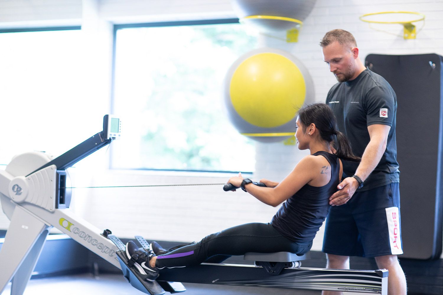 Fitness professionals demonstrating proper workout form in well-equipped exercise studio.