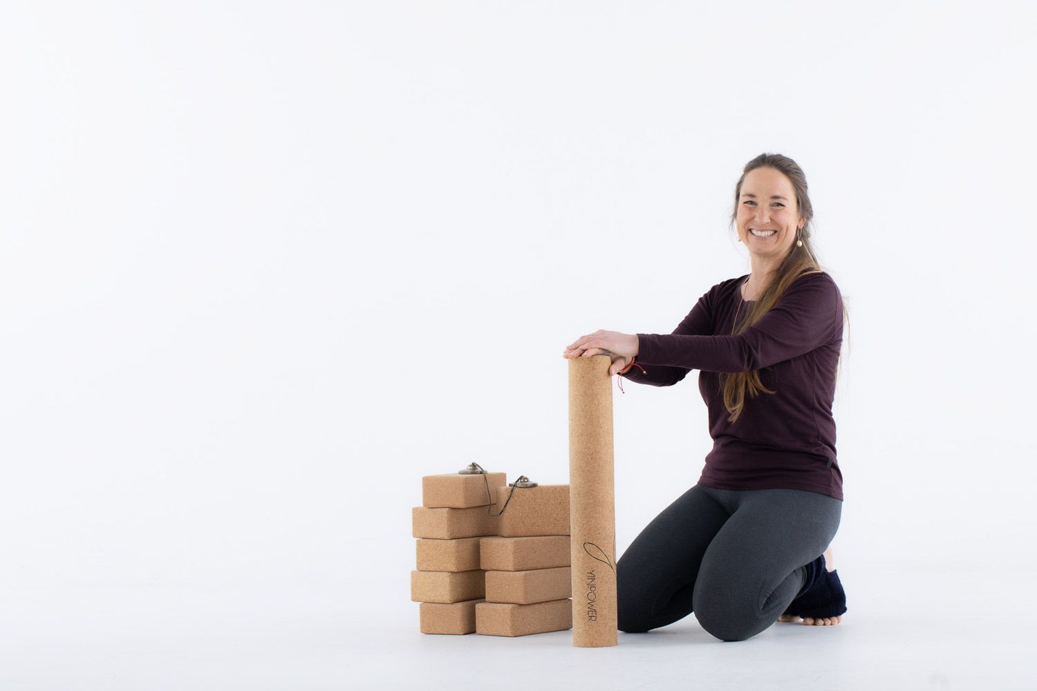 Person demonstrating yoga poses with cork blocks on white background.