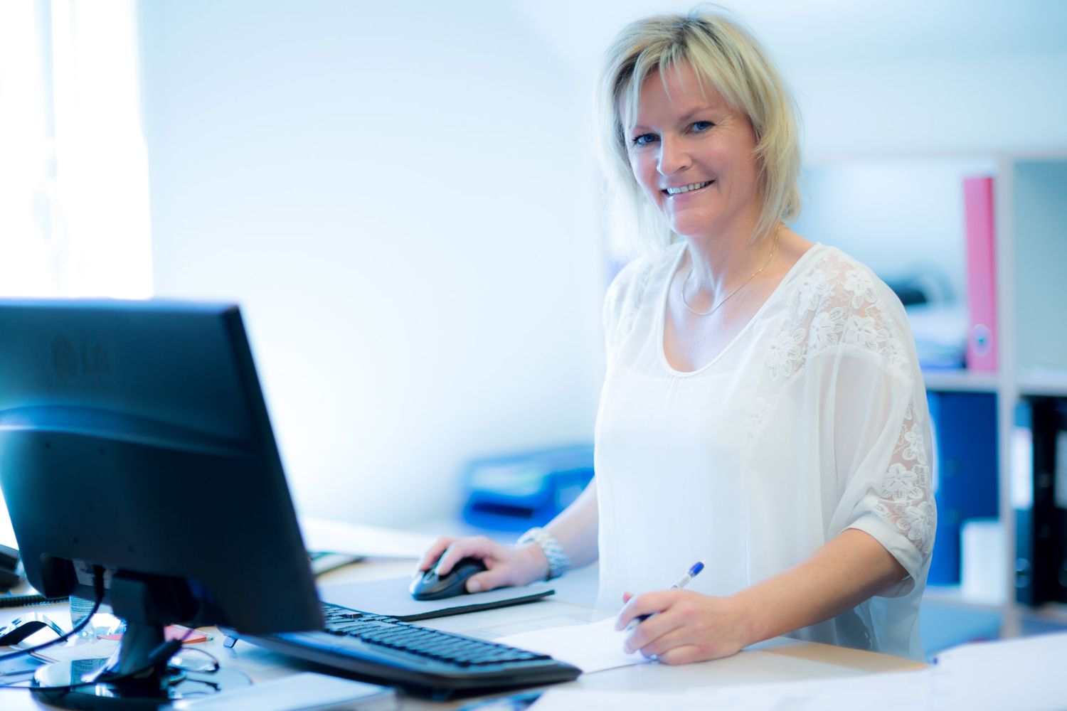 Professional team members working at computer workstations in bright corporate environment.