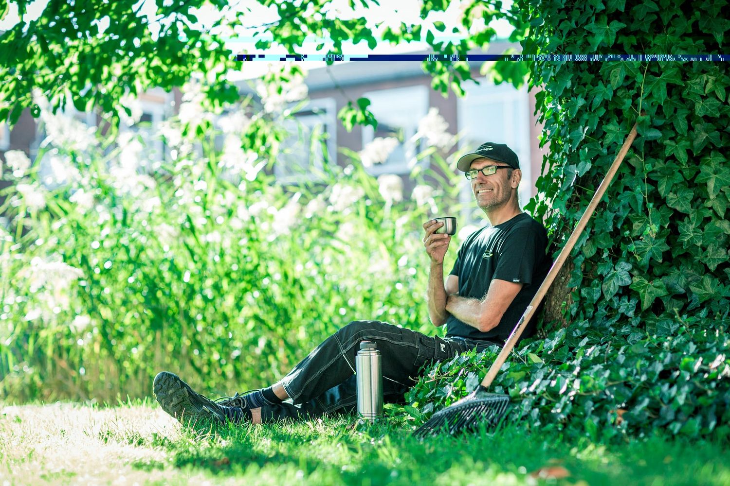 Landscaper spraying pesticide treatment in lush green garden area.