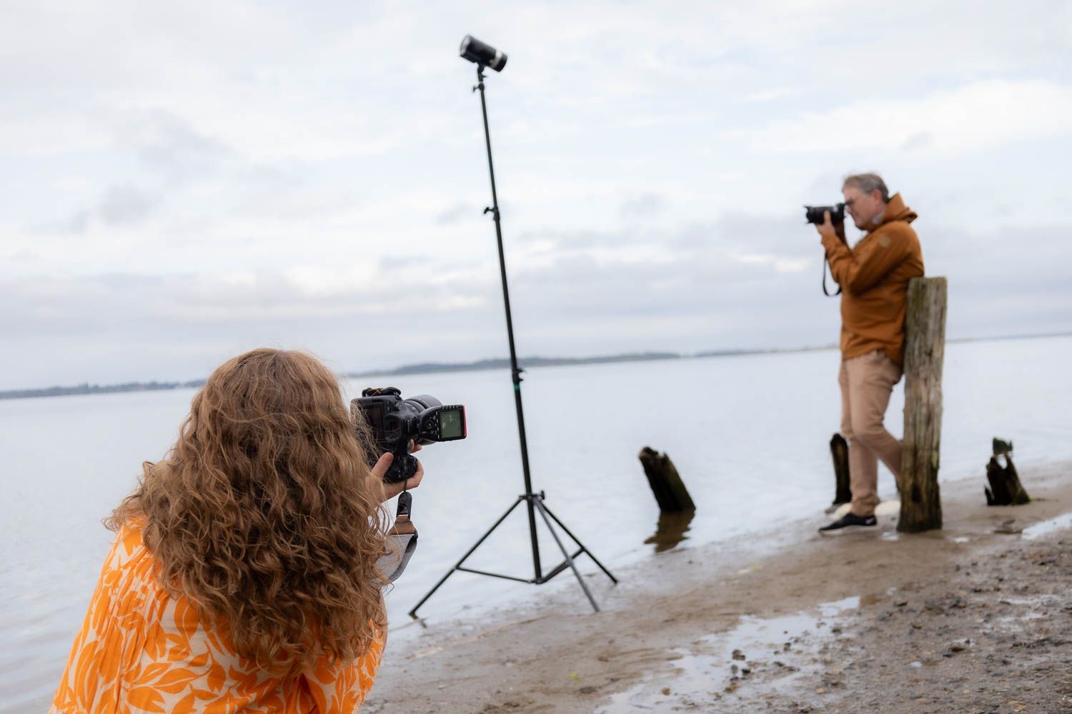 Photographers capturing shots along a misty shoreline with camera equipment.