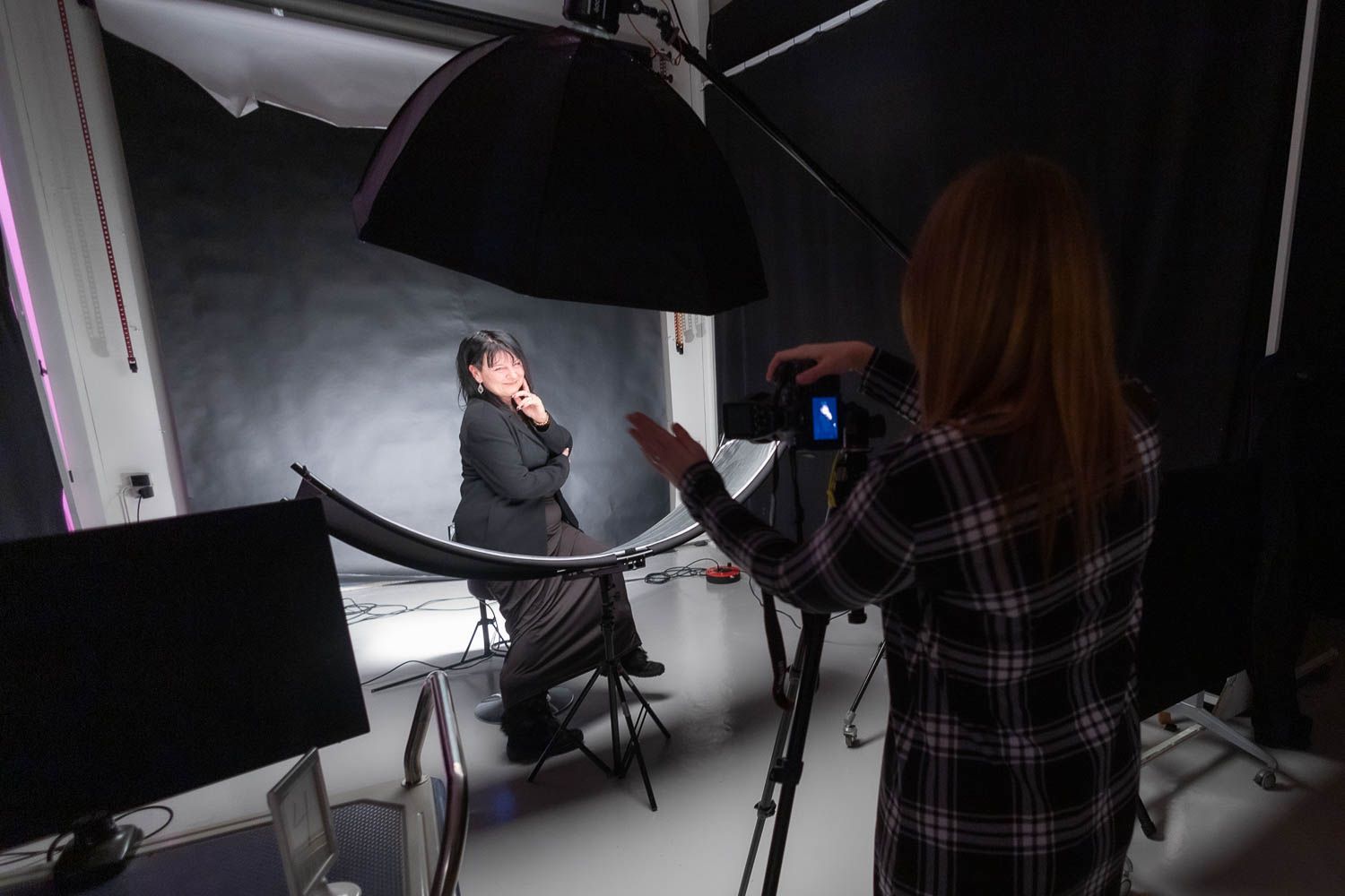 Dark studio environment with professional lighting equipment and photographers at work.