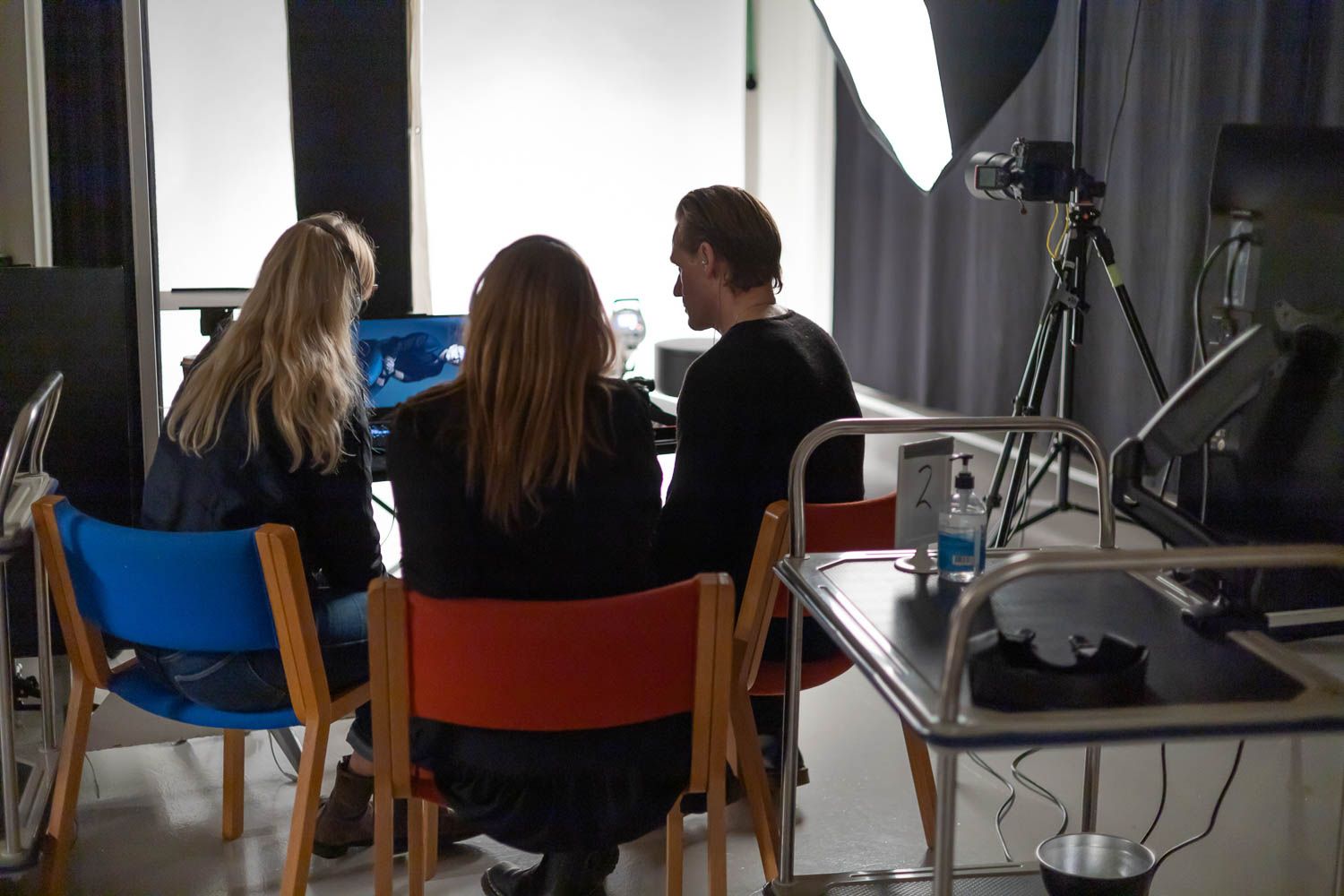 Behind the scenes view of photographers working in a professional studio with softboxes and lighting.