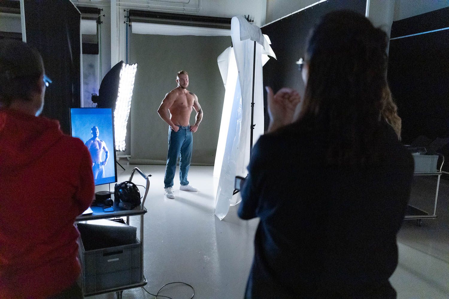 Photography crew working in dark studio with bright lighting setup and monitors.