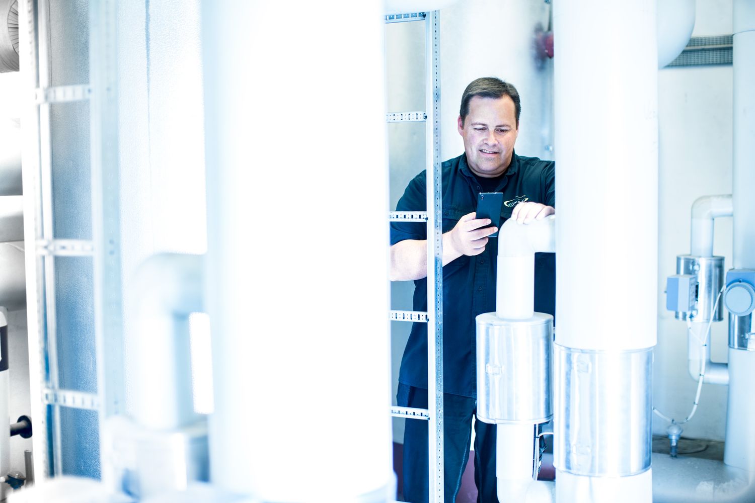 Technician checking equipment readings in bright industrial hallway.