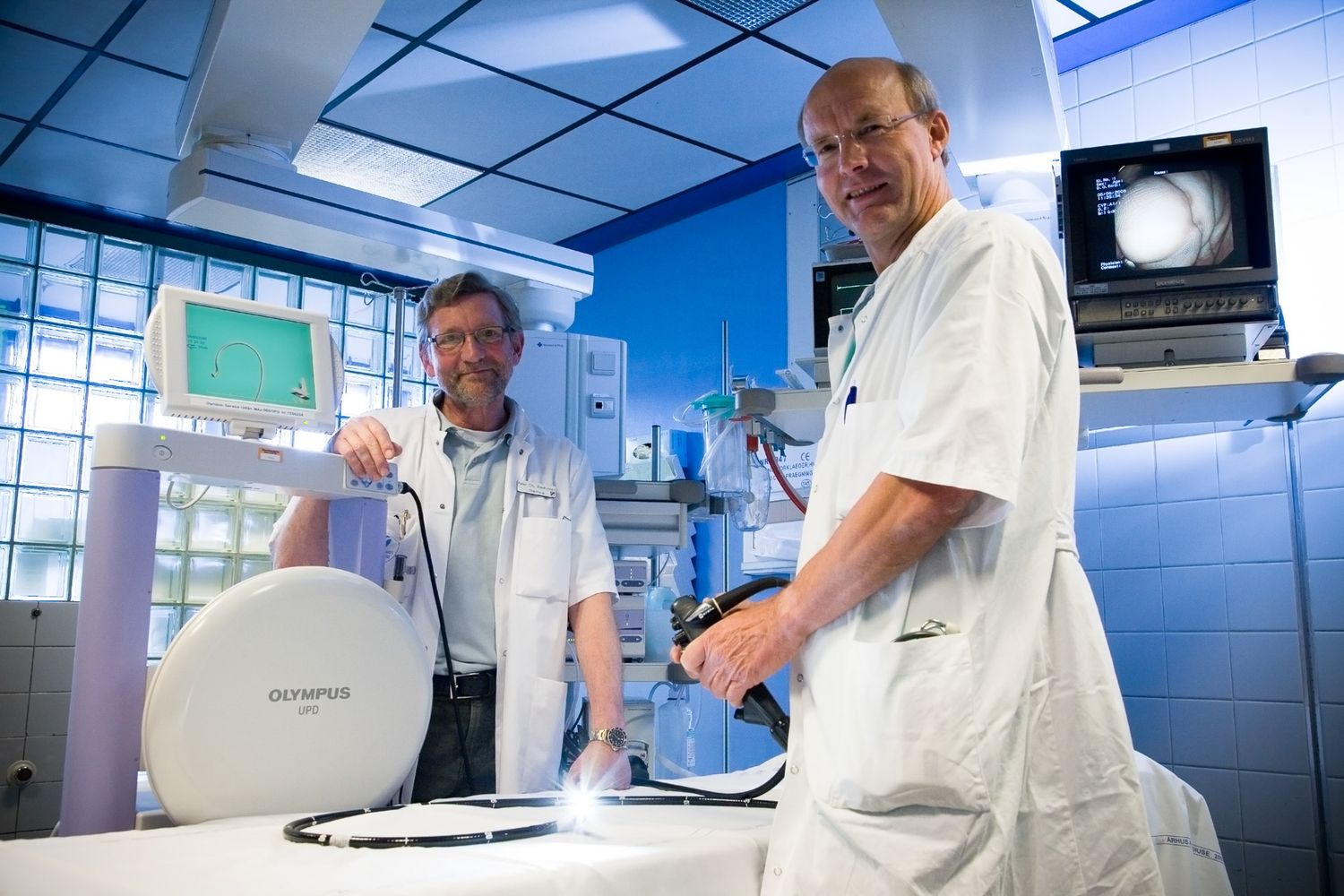 Modern hospital hallway with medical staff and equipment under fluorescent lighting.