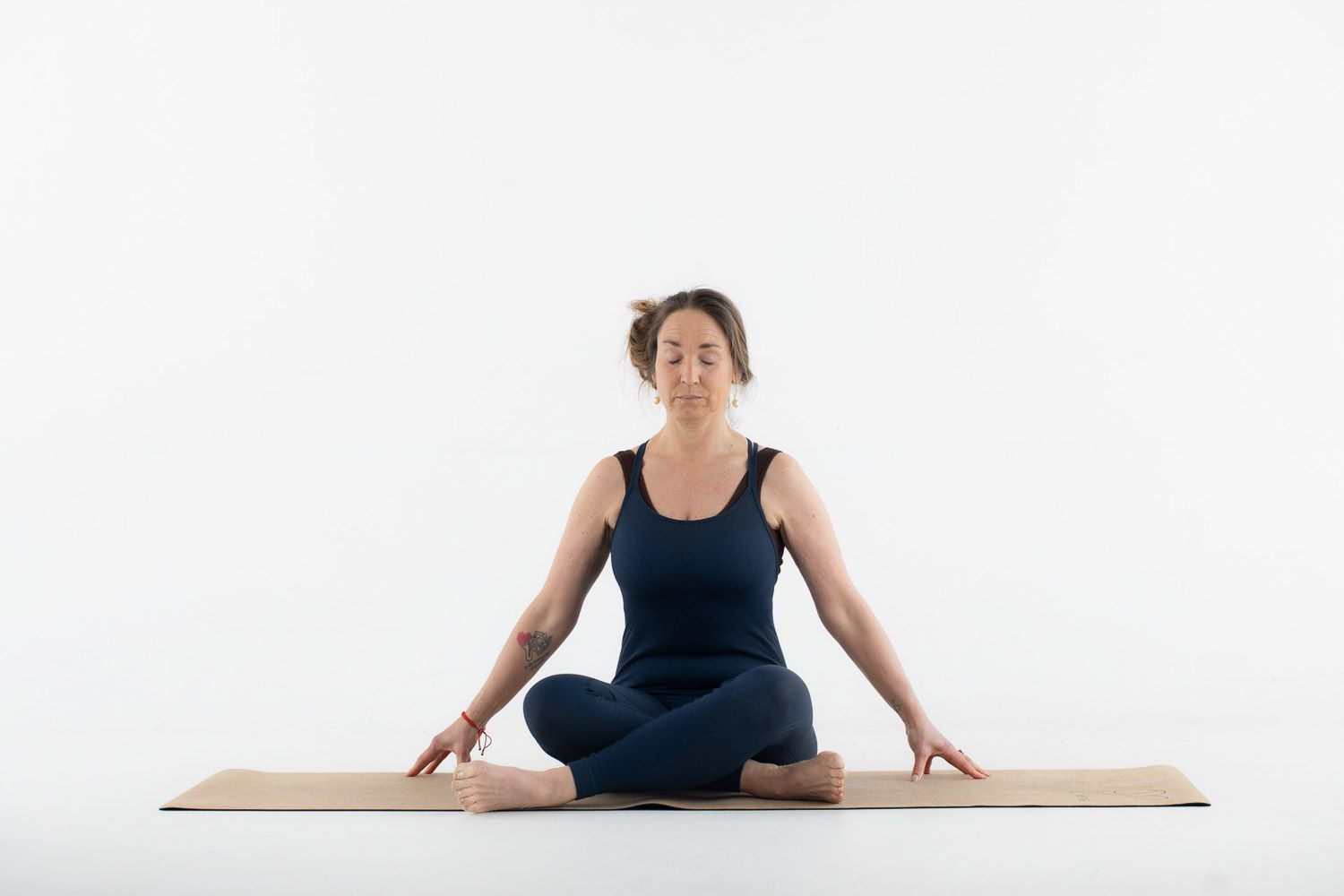 Person showing various seated yoga positions on exercise mat in studio setting.