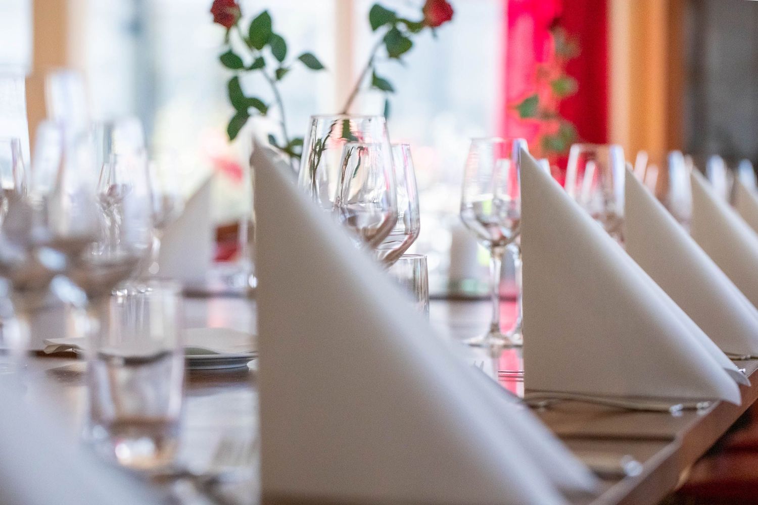 Formal table settings with folded white napkins and wine glasses in a row.