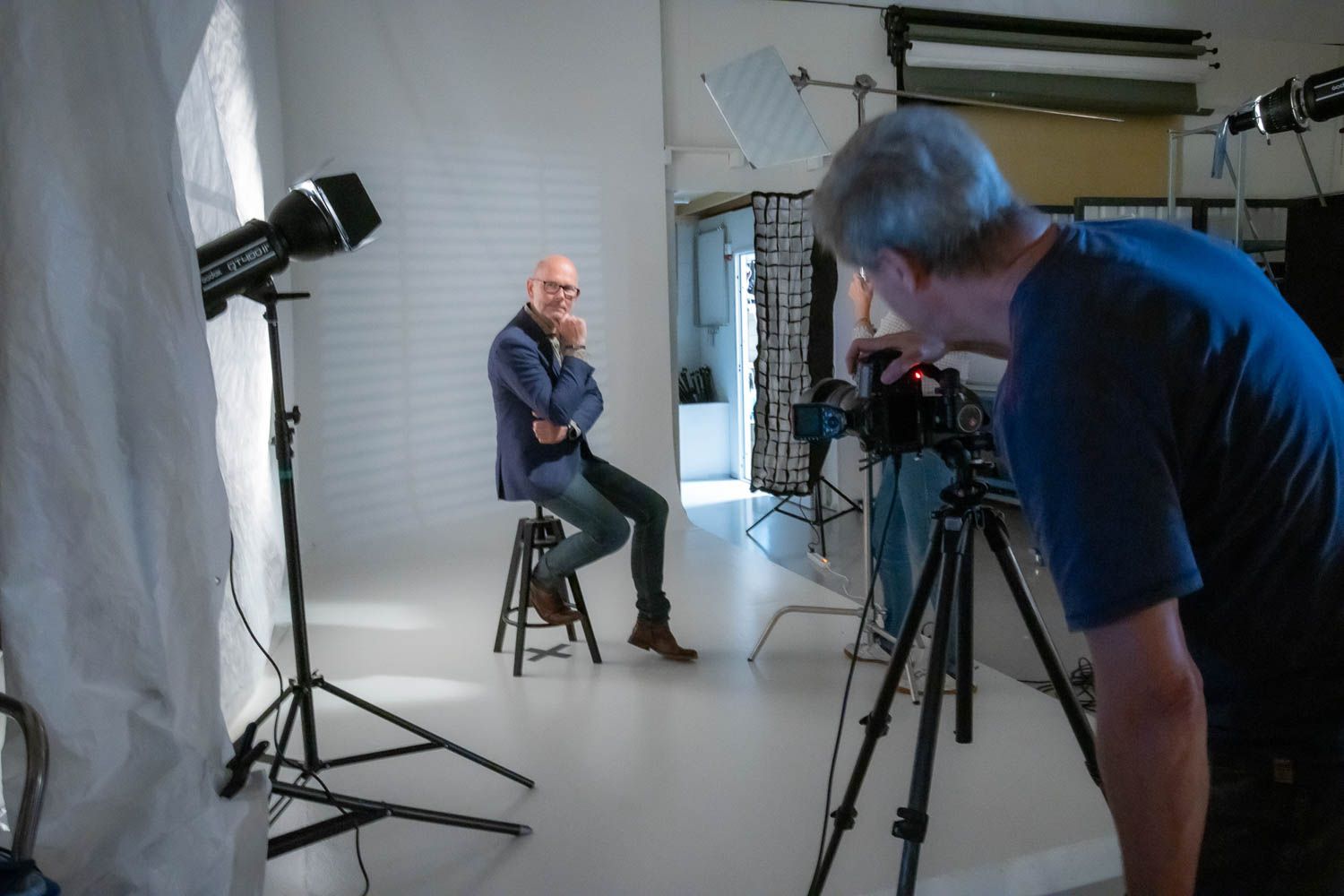Photography team working in professional studio with lighting and camera equipment.
