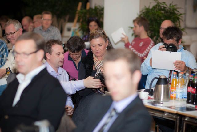 Business meeting with professionals seated at tables in a conference setting.