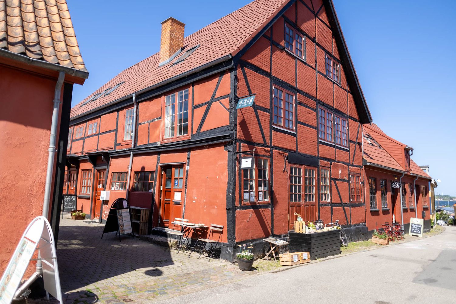 Traditional red half-timbered building with terracotta roof tiles in a historic town setting.