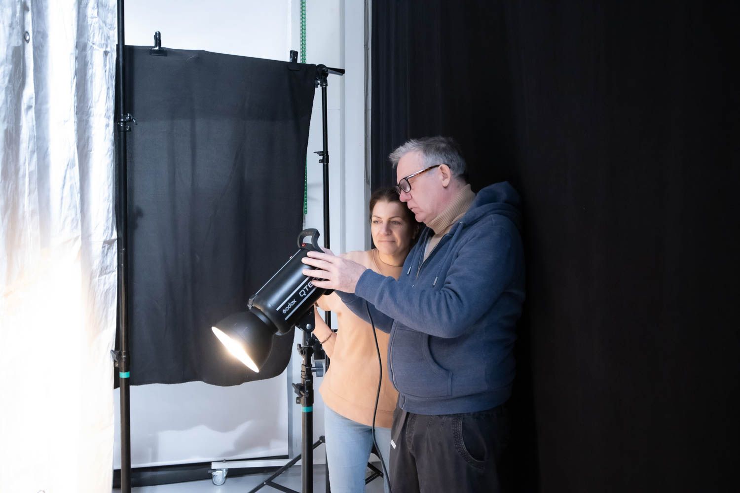 Photography instructor demonstrating lighting techniques with studio equipment.