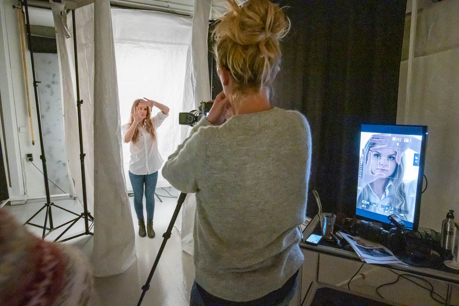 Studio photography session in progress with monitors and lighting equipment visible.