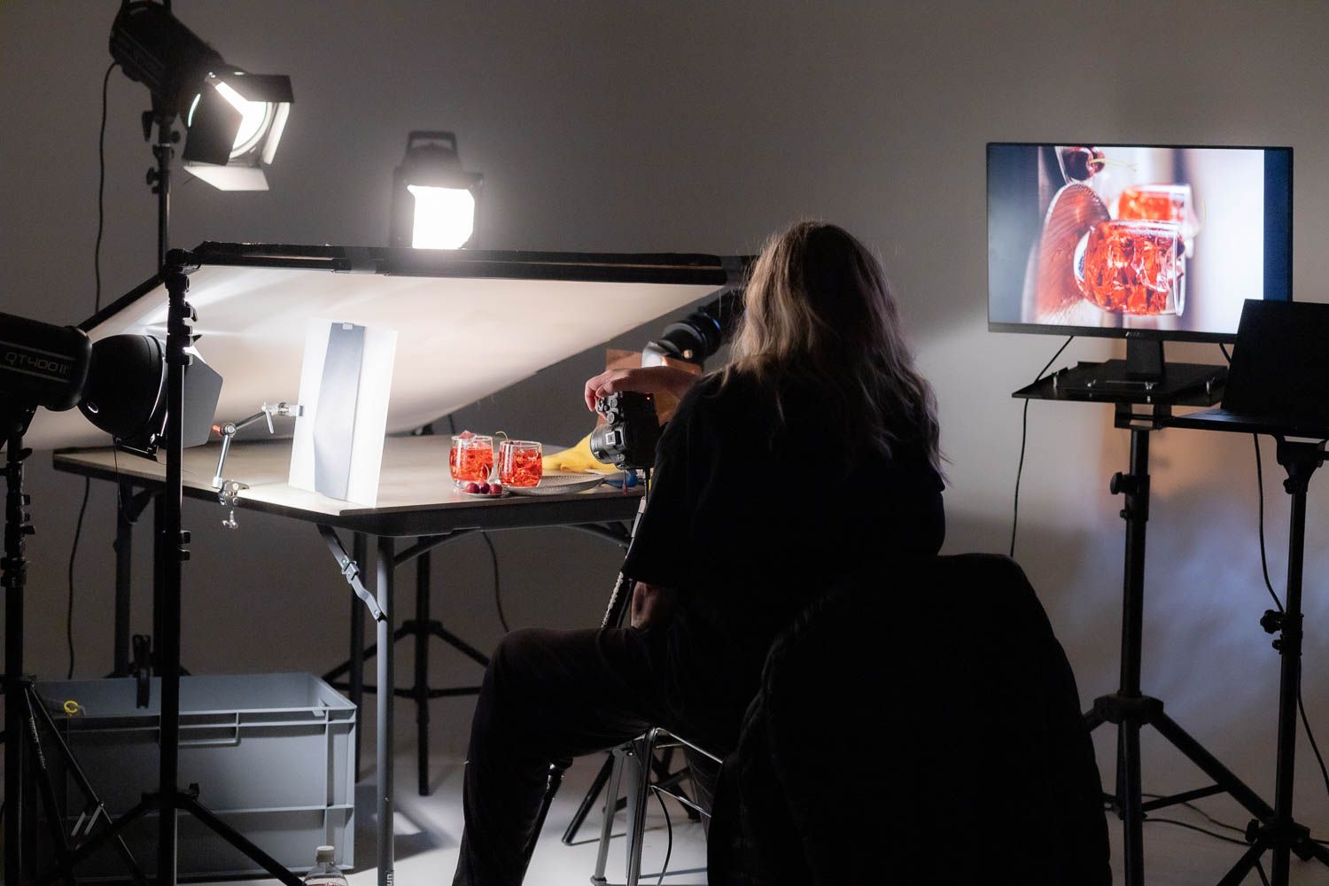 Photography studio interior with professional lighting equipment and monitors displaying images.