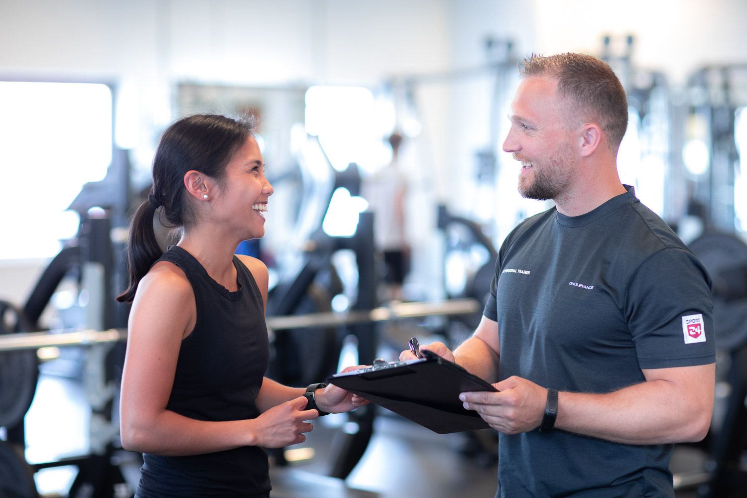 Fitness professionals consulting with clients in a contemporary gym environment.