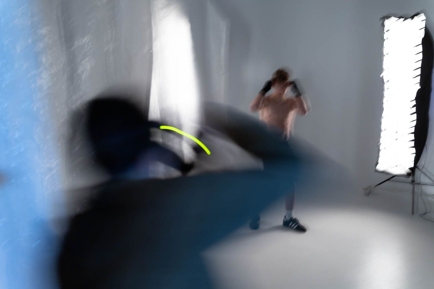 Blurred motion photography shoot in white studio space with professional lighting setup.