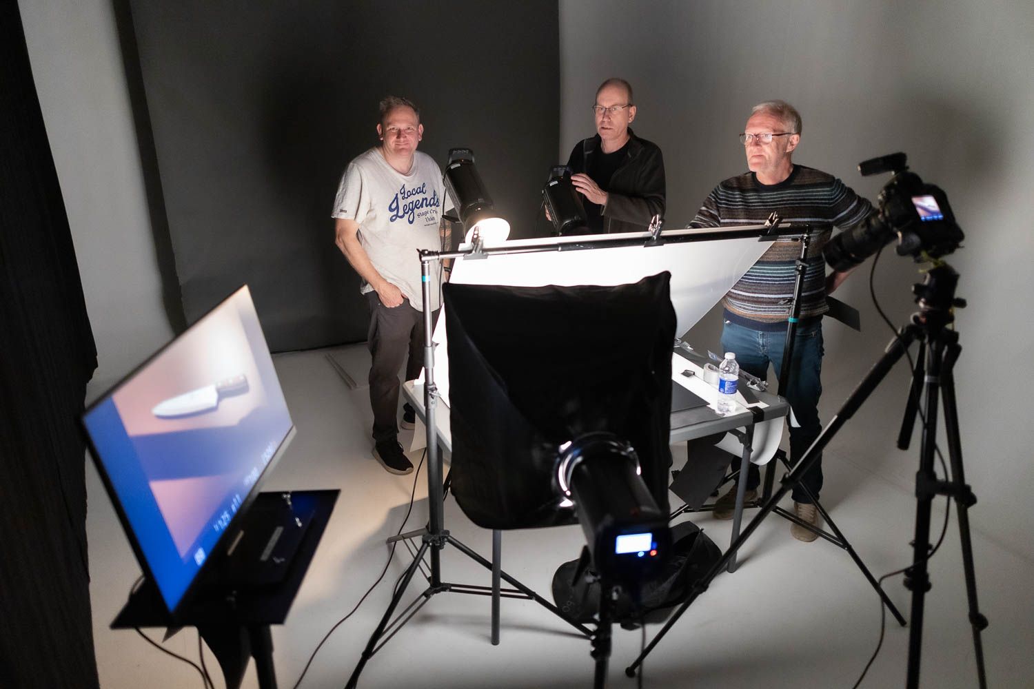 Studio photography session with lighting equipment and white backdrop setup.
