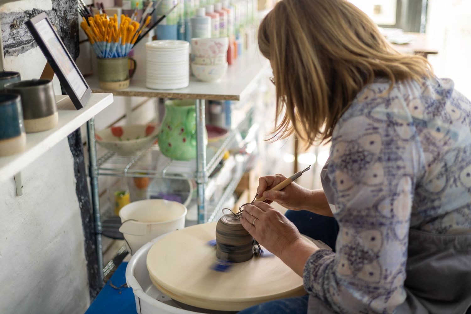Pottery studio workspace with tools and materials arranged near natural lighting.