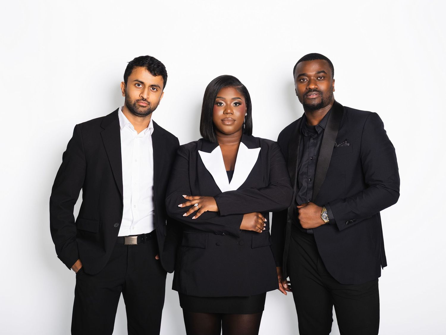 Three confident professionals in black suits posing together against a white background.